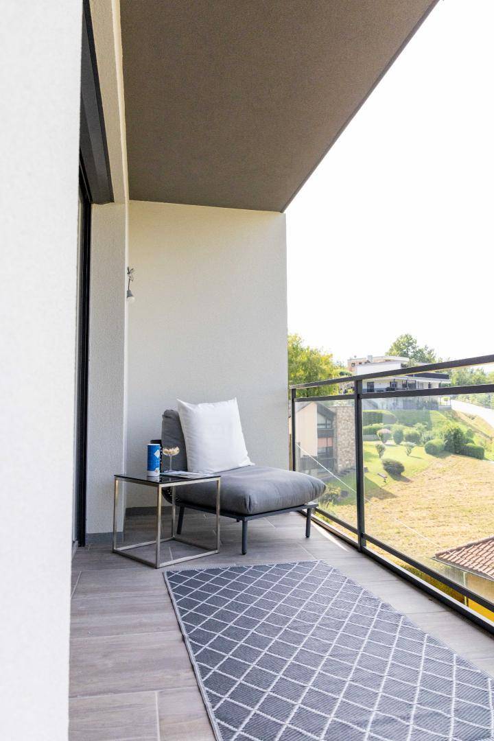 Gemütlicher Balkon mit modernem Sessel, Beistelltisch und Teppich für entspannte Stunden im Freien.