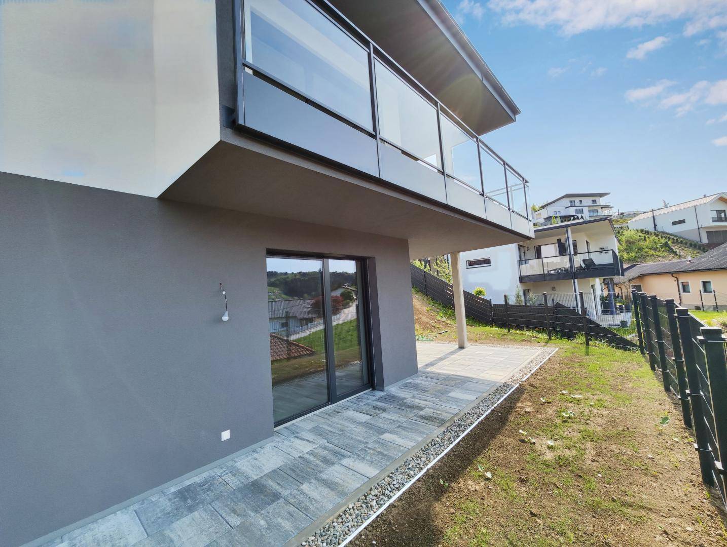Gepflasterte Terrasse im Erdgeschoss mit Zugang zum Garten und Blick auf die Umgebung.