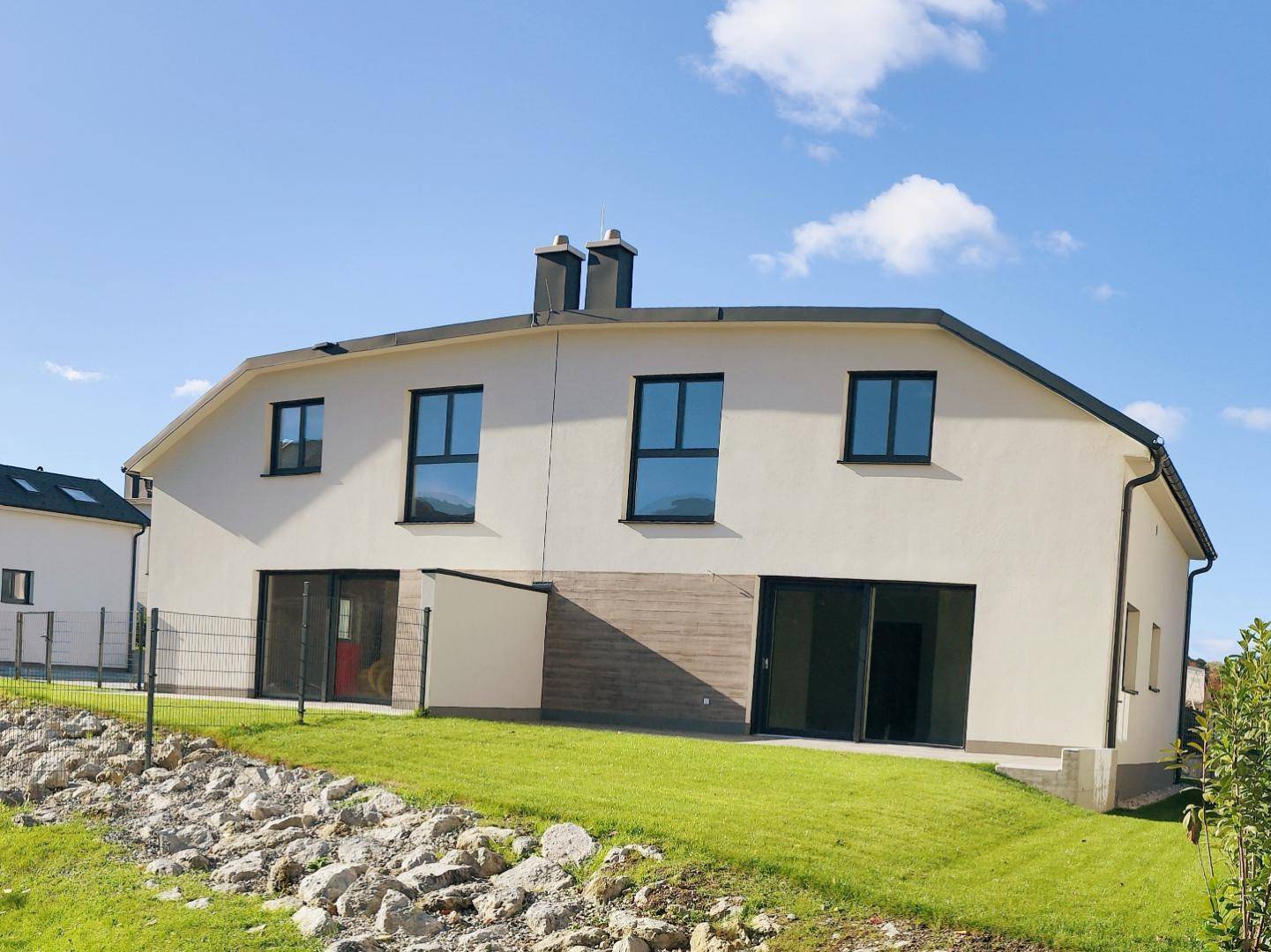 Rückansicht eines modernen Reihenhauses mit großen Fenstern und heller Fassade.