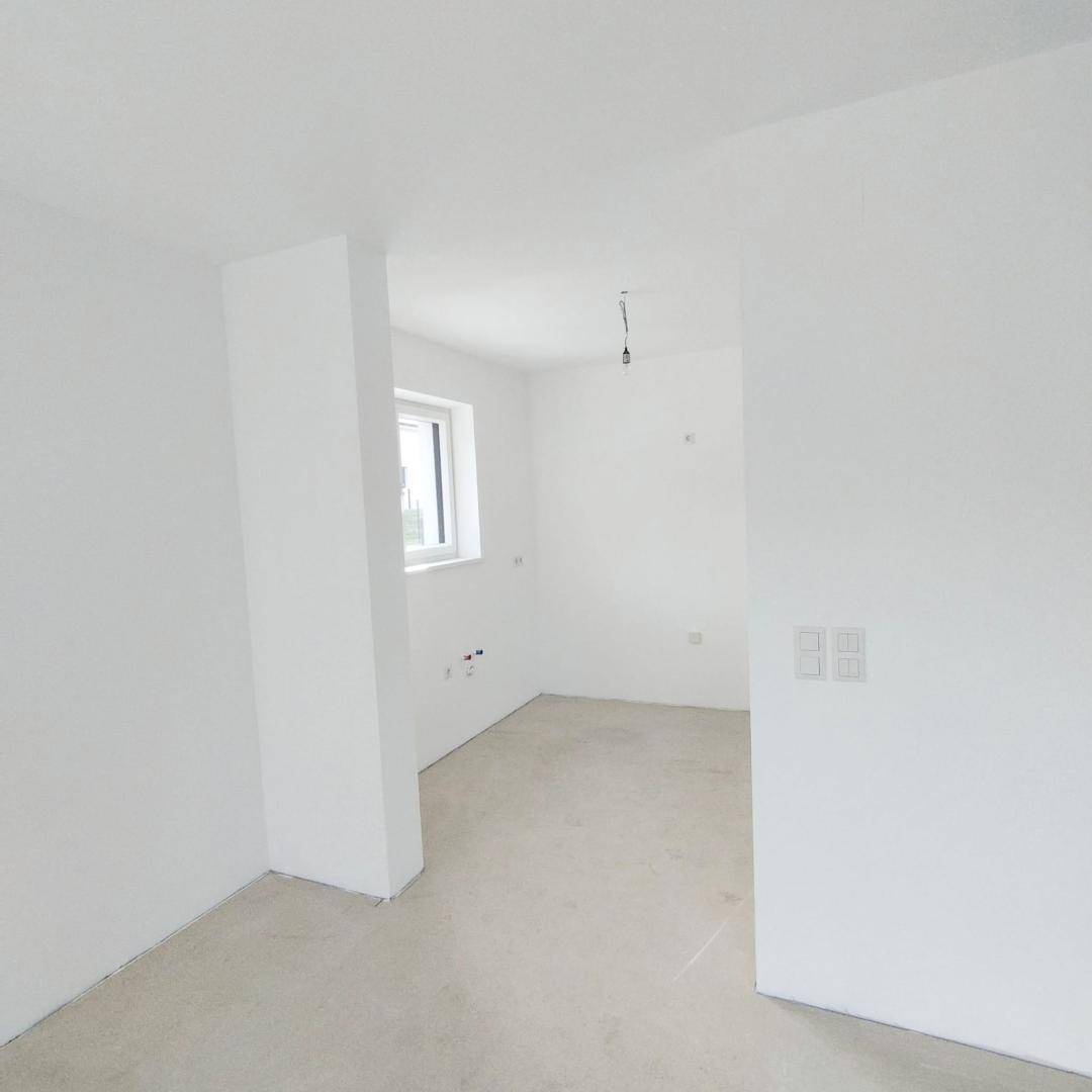 Unmöblierter Raum mit weiß gestrichenen Wänden und einem kleinen Fenster.