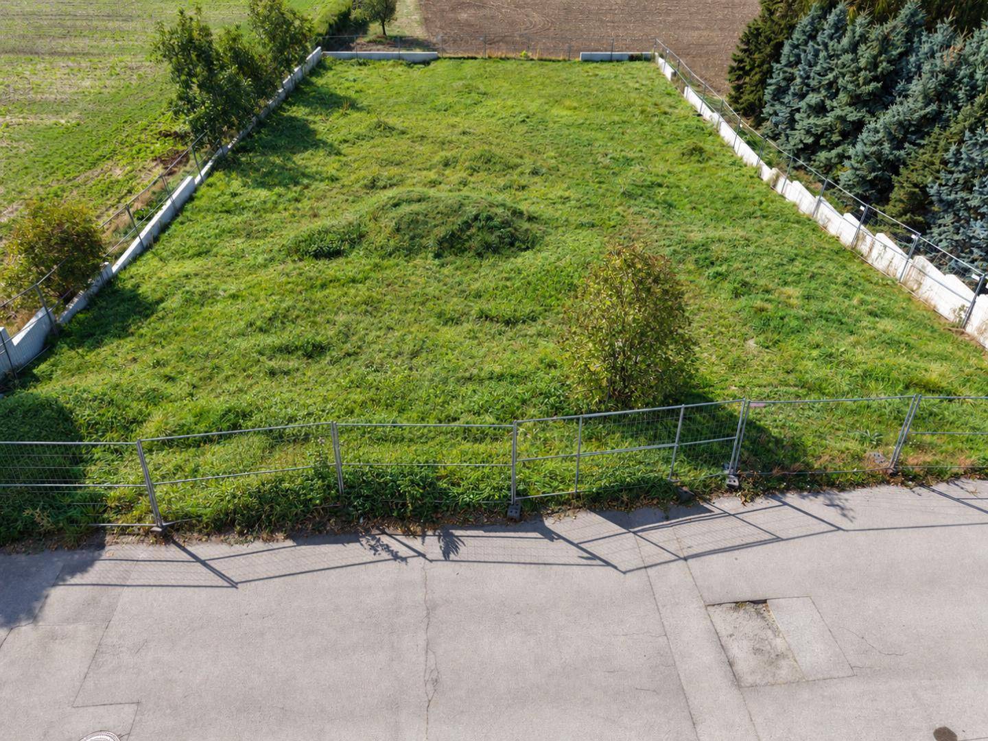 Luftaufnahme eines umzäunten Grundstücks mit grüner Wiese und angrenzender Straße.