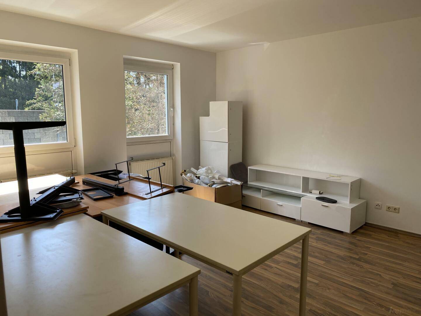 Wohnzimmer mit Laminatboden, großen Fenstern und viel natürlichem Licht, unmöbliert.