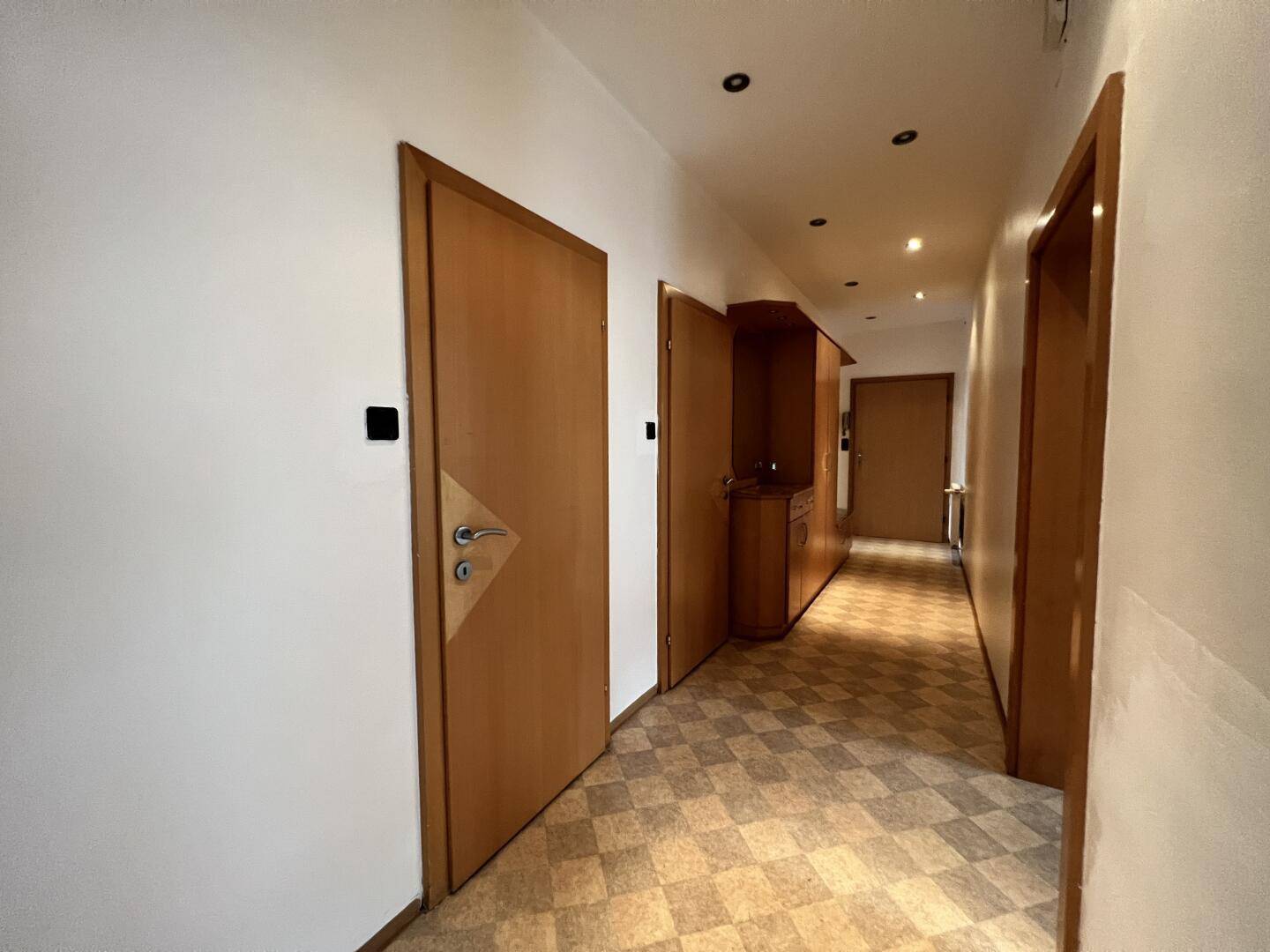 Heller Flur mit mehreren Holztüren und Einbauschrank, der den Zugang zu den Wohnräumen ermöglicht.