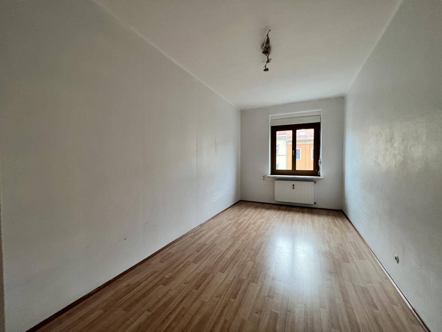 Heller Raum mit Laminatboden und einem Fenster, bereit zur individuellen Gestaltung.