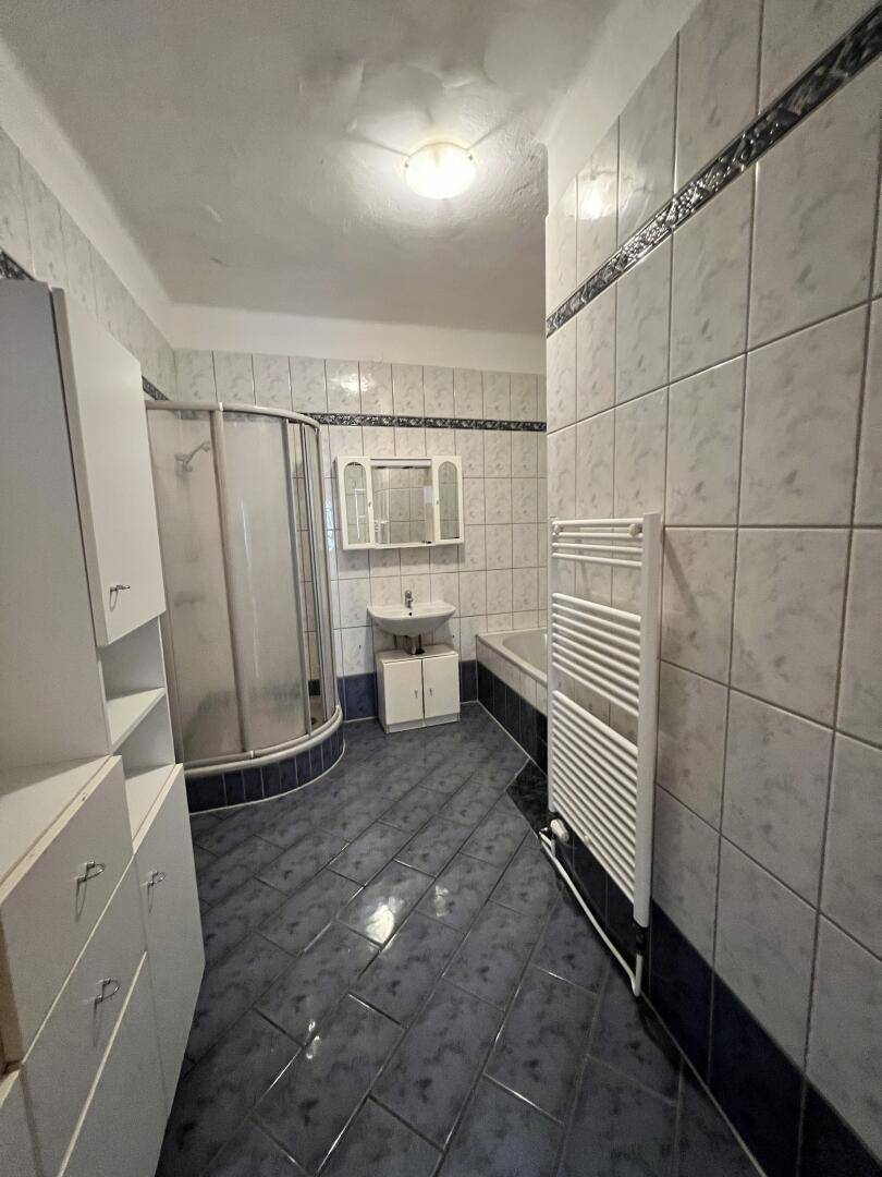 Gefliestes Badezimmer mit Dusche, Badewanne und beheiztem Handtuchhalter.
