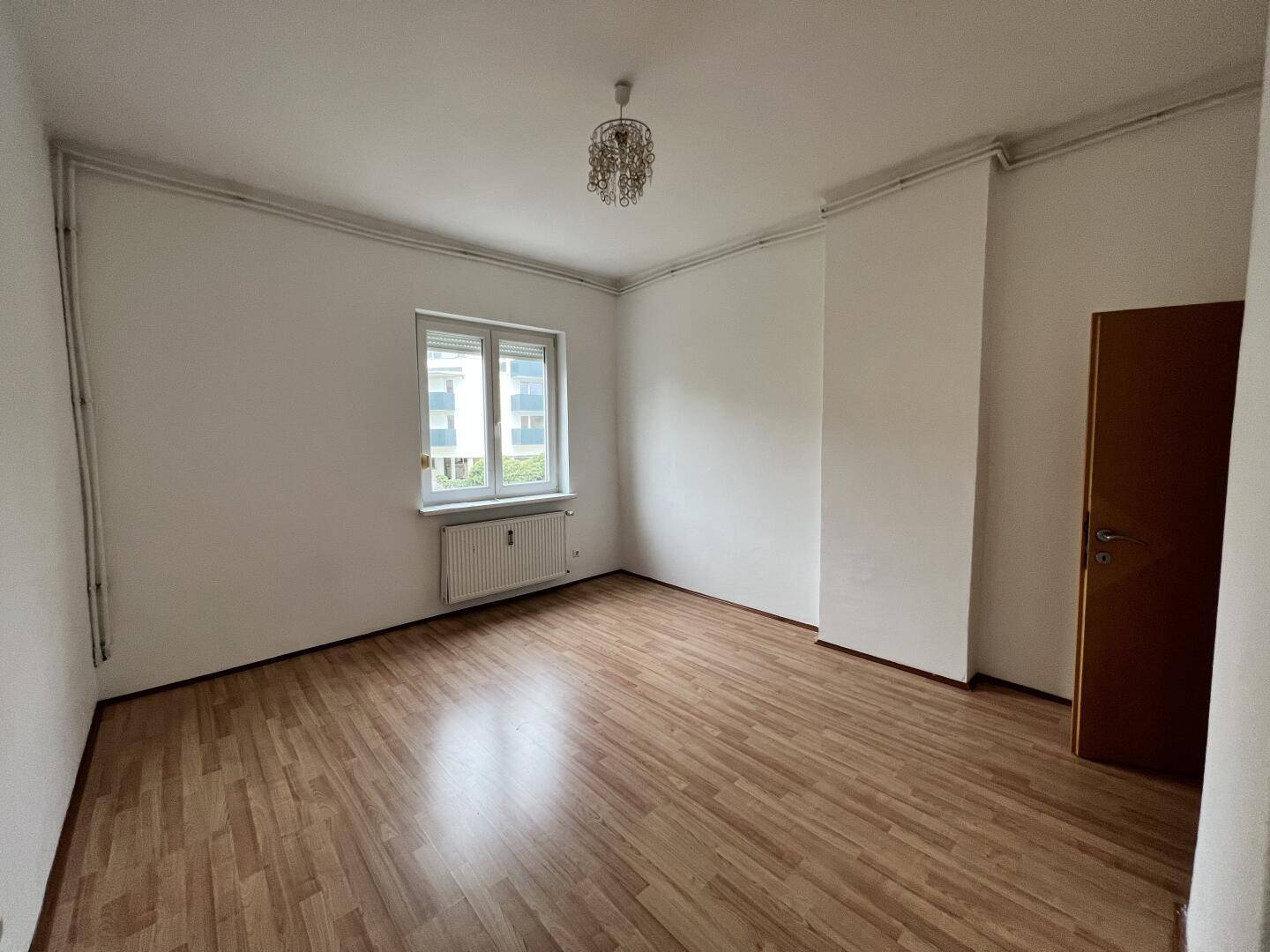 Helles Schlafzimmer mit Laminatboden und großem Fenster, bietet einen angenehmen Ausblick.