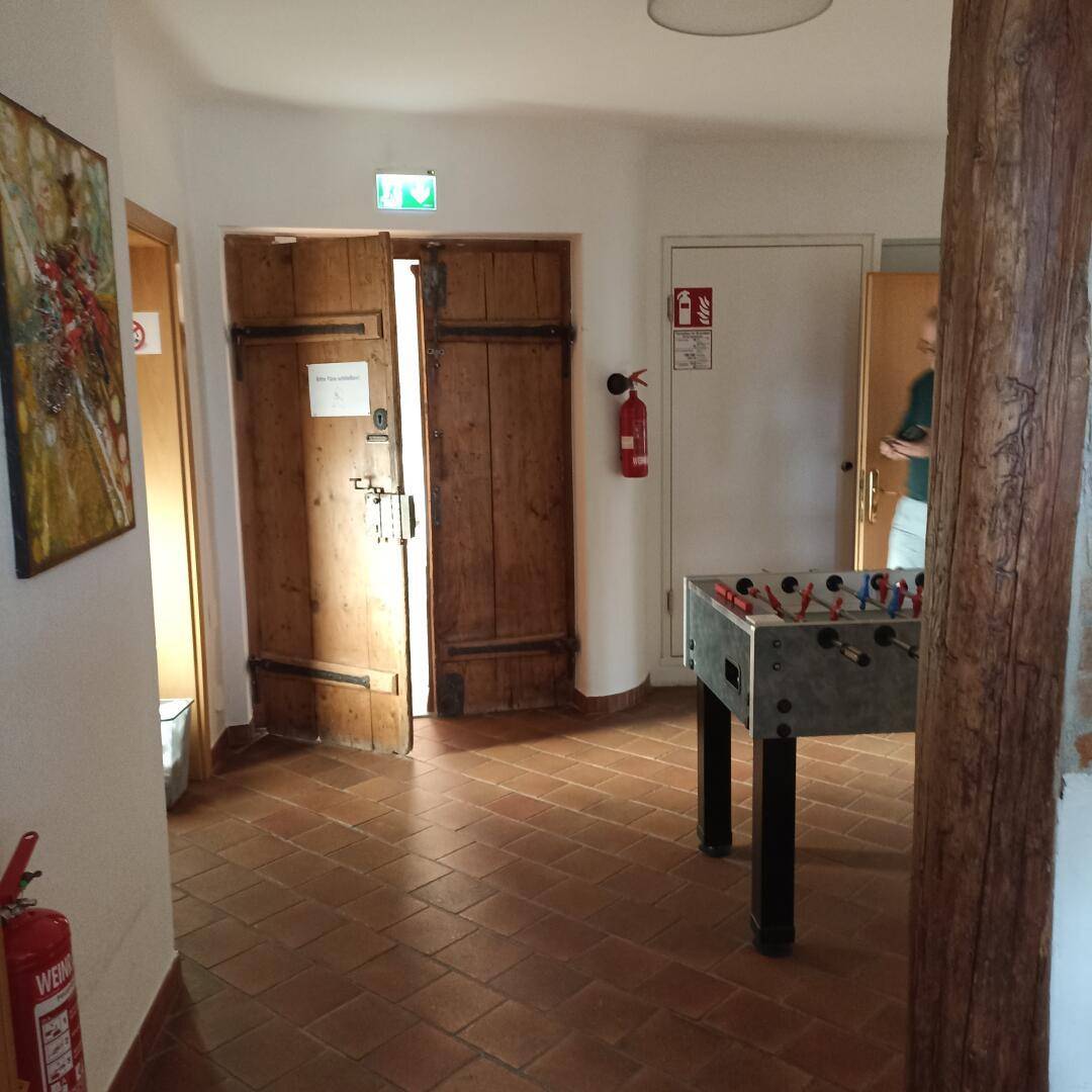 Flur mit Terrakottafliesen, Holztüren und einem Tischfußballspiel.