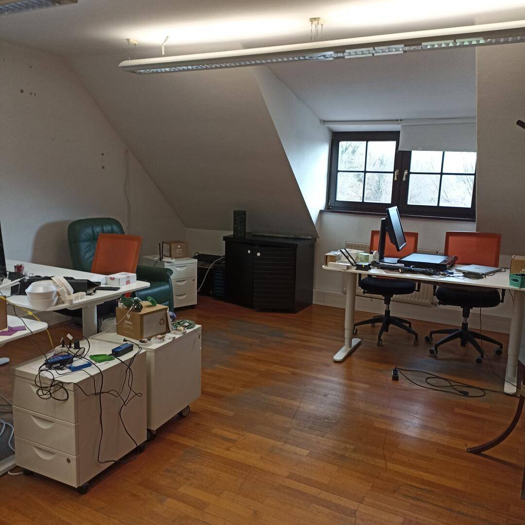 Dachgeschossbüro mit mehreren Arbeitsplätzen, Holzboden und Stauraum unter der Dachschräge.