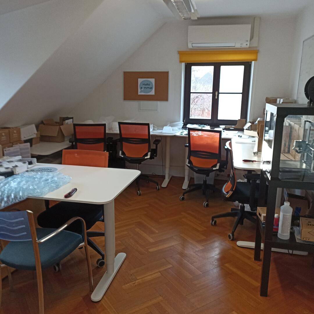 Dachgeschossbüro mit mehreren Arbeitsplätzen, Holzboden und Klimaanlage unter der Dachschräge.