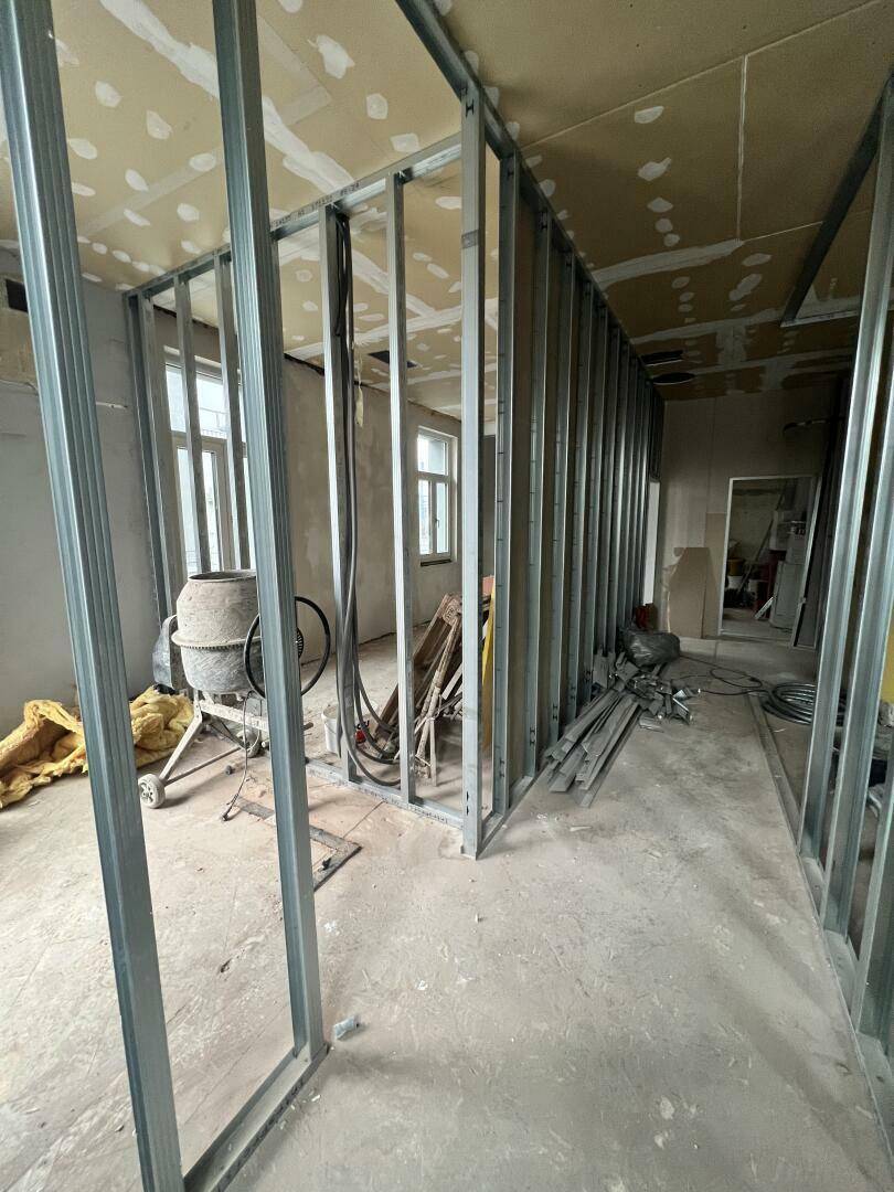 Innenraum im Rohbau mit Metallständerwerk für Trockenbauwände und Baustoffen auf dem Betonboden.