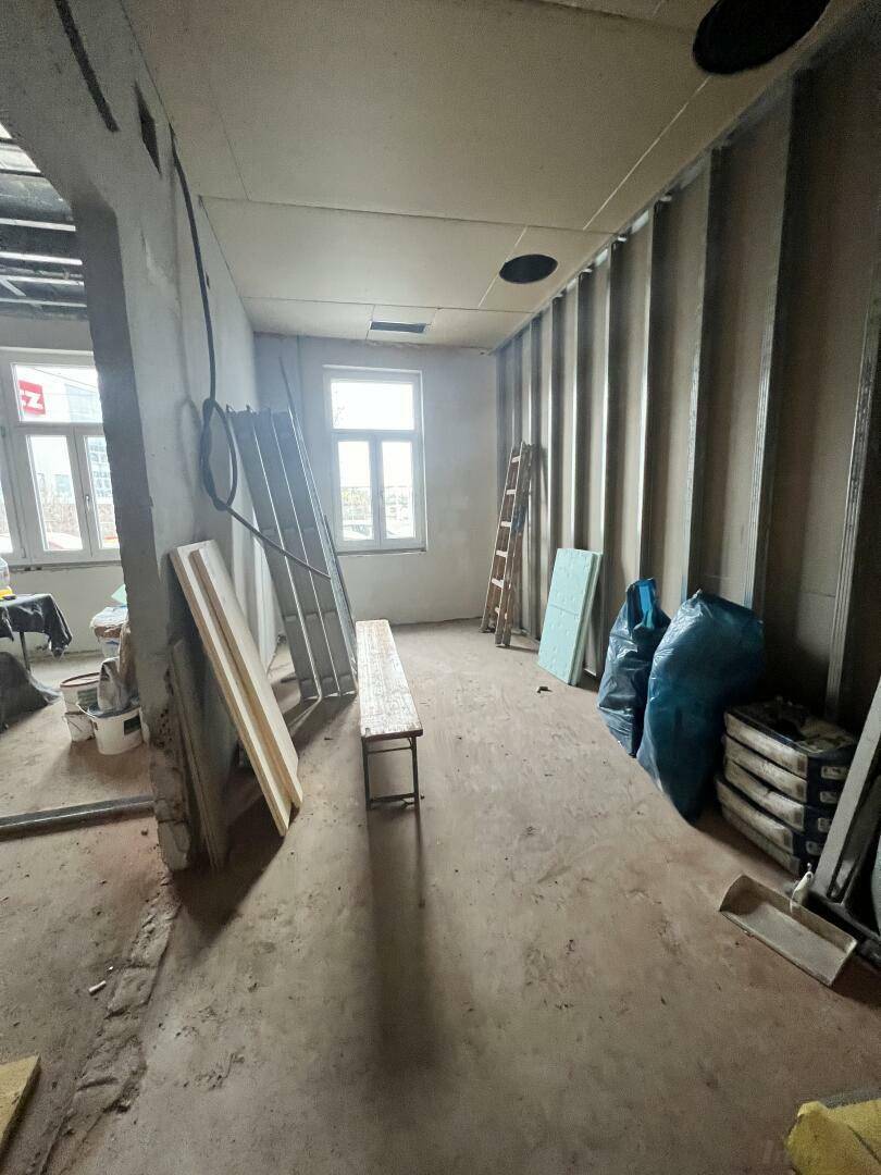 Baustelle mit unverputzten Wänden, einem Fenster und Baumaterialien auf dem Betonboden, bereit für den Ausbau.