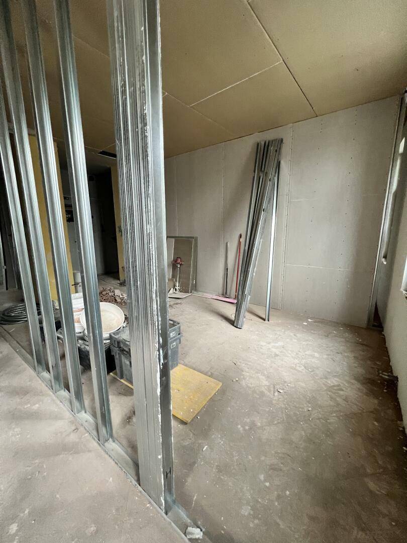 Innenraum im Rohbau mit Metallständerwerk und Gipskartonplatten an den Wänden, bereit für die Fertigstellung.