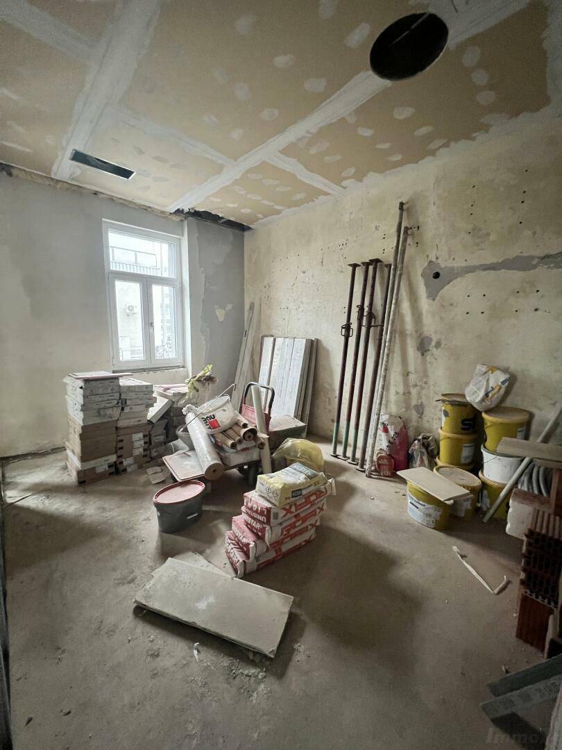 Raum im Rohbau mit gestapelten Baustoffen, einem Fenster und unverputzten Wänden, bereit für die Renovierung.