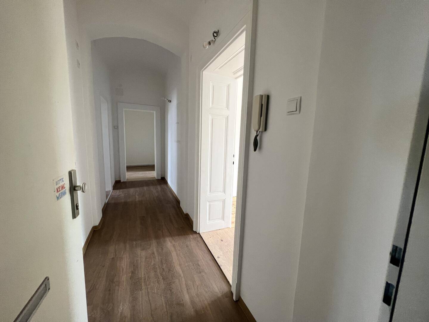 Heller Flur mit Holzboden und mehreren Türen, der zu verschiedenen Räumen führt.