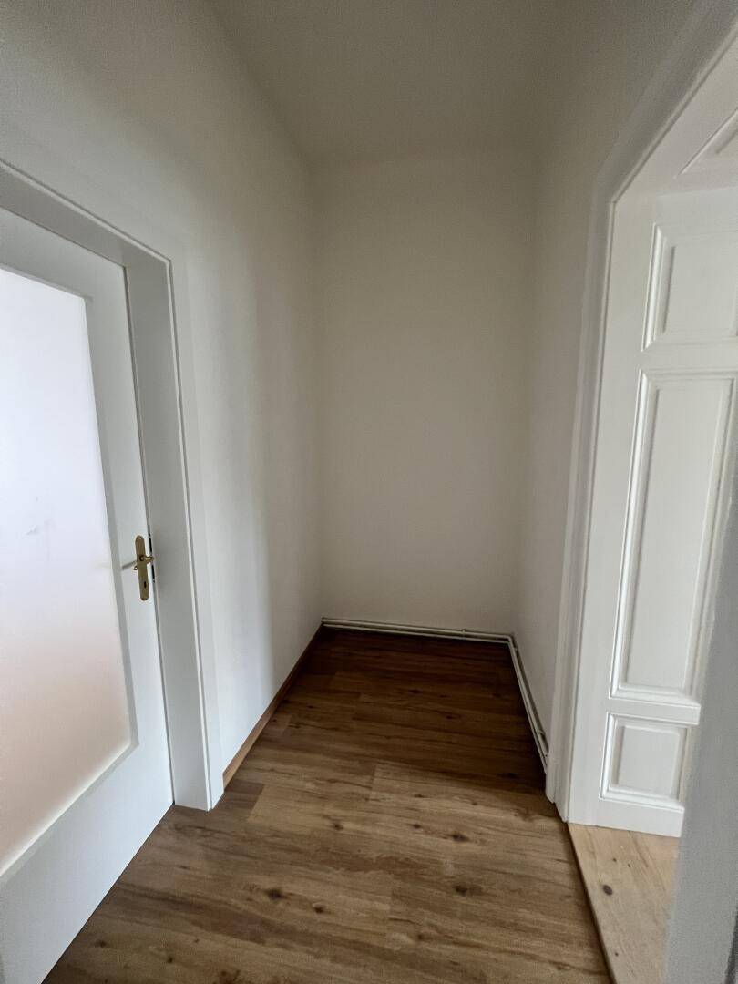 Kleiner, leerer Raum mit Holzboden, ideal als Abstellraum oder begehbarer Kleiderschrank.