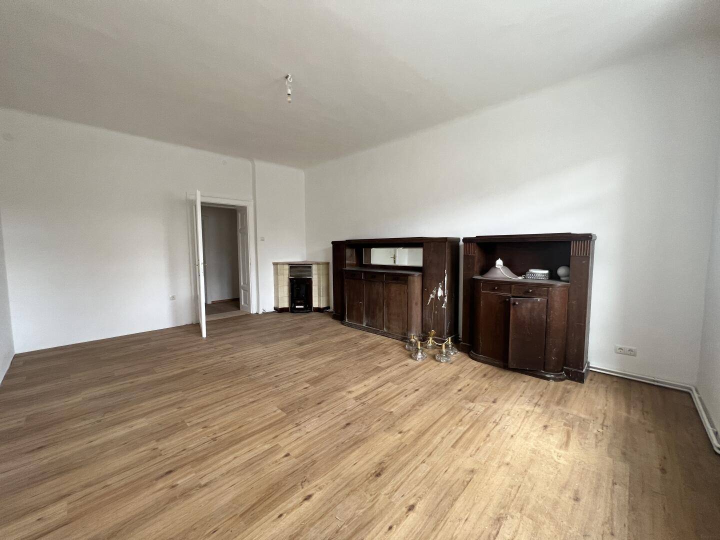 Großes Wohnzimmer mit Holzboden, antiken Möbeln und einem traditionellen Ofen in der Ecke.