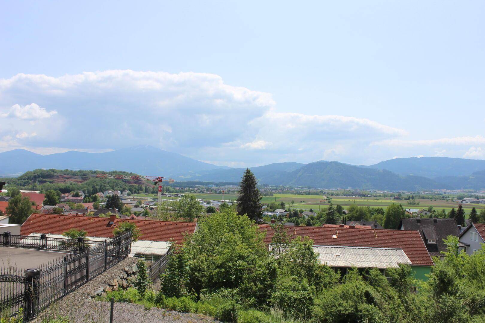Weitläufiger Blick über eine Wohnsiedlung mit grünen Flächen und einer beeindruckenden Bergkulisse.