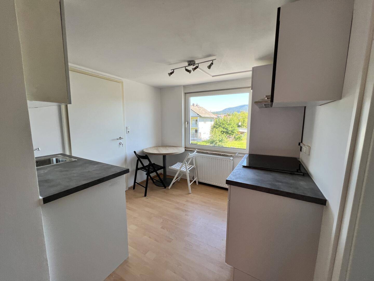 Kleine Küche mit Esstisch, Fenster und Blick ins Grüne, ideal für Singles oder Paare.