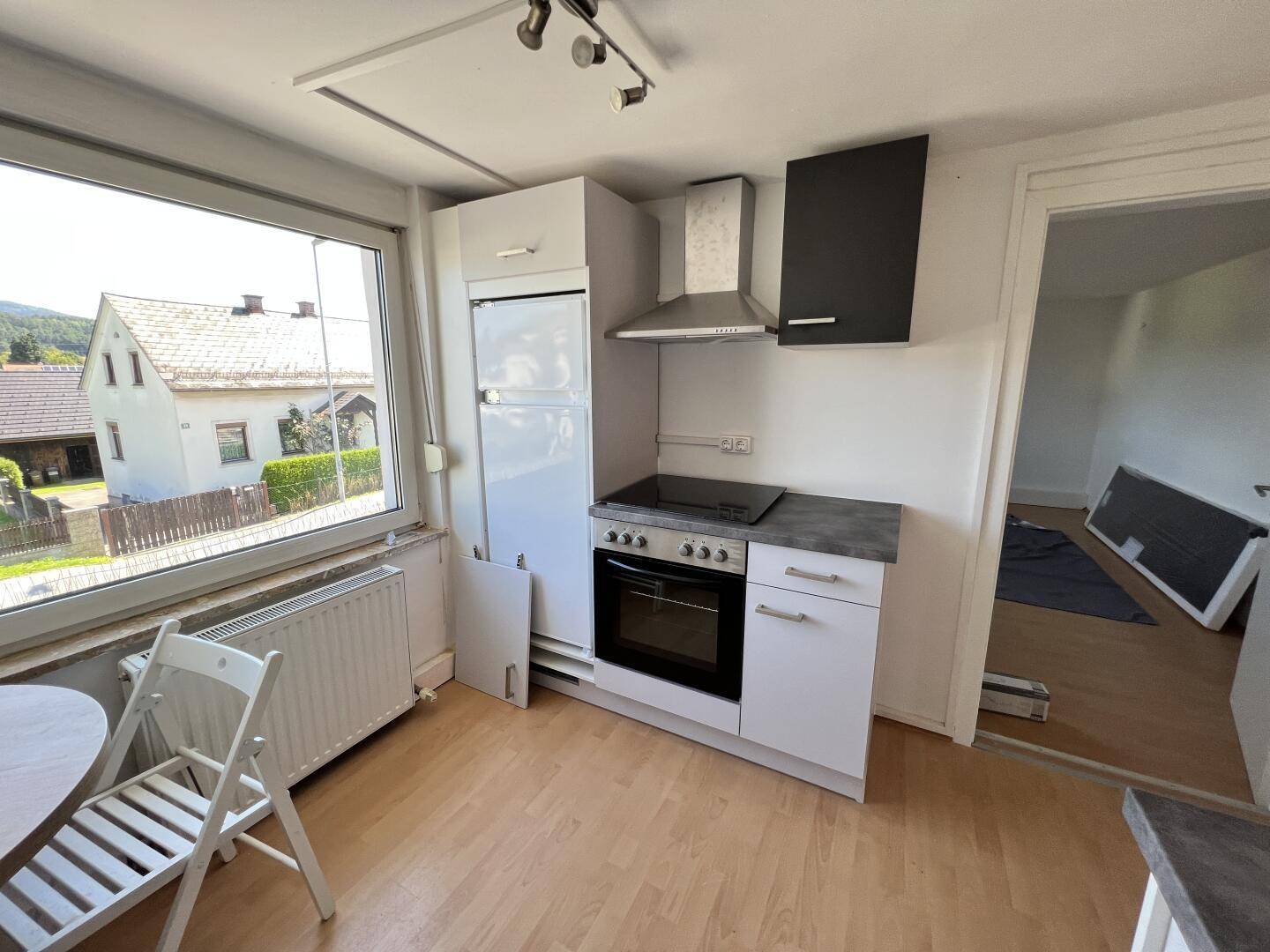 Funktionale Küche mit Fenster, Einbaugeräten und Blick auf die umliegende Wohngegend.