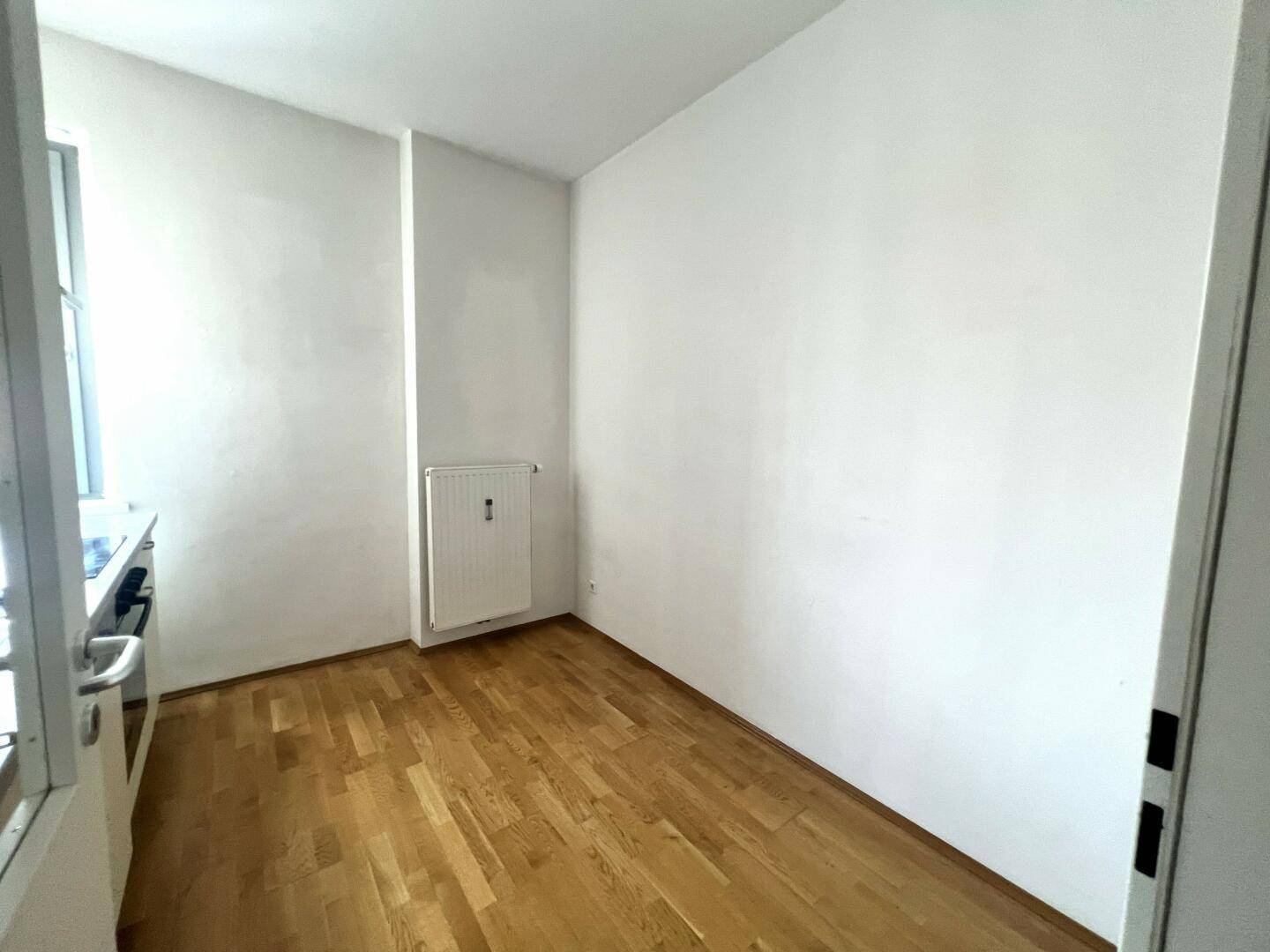 Kleiner, heller Raum mit Parkettboden und Fenster, ideal als Arbeitszimmer oder Abstellraum.