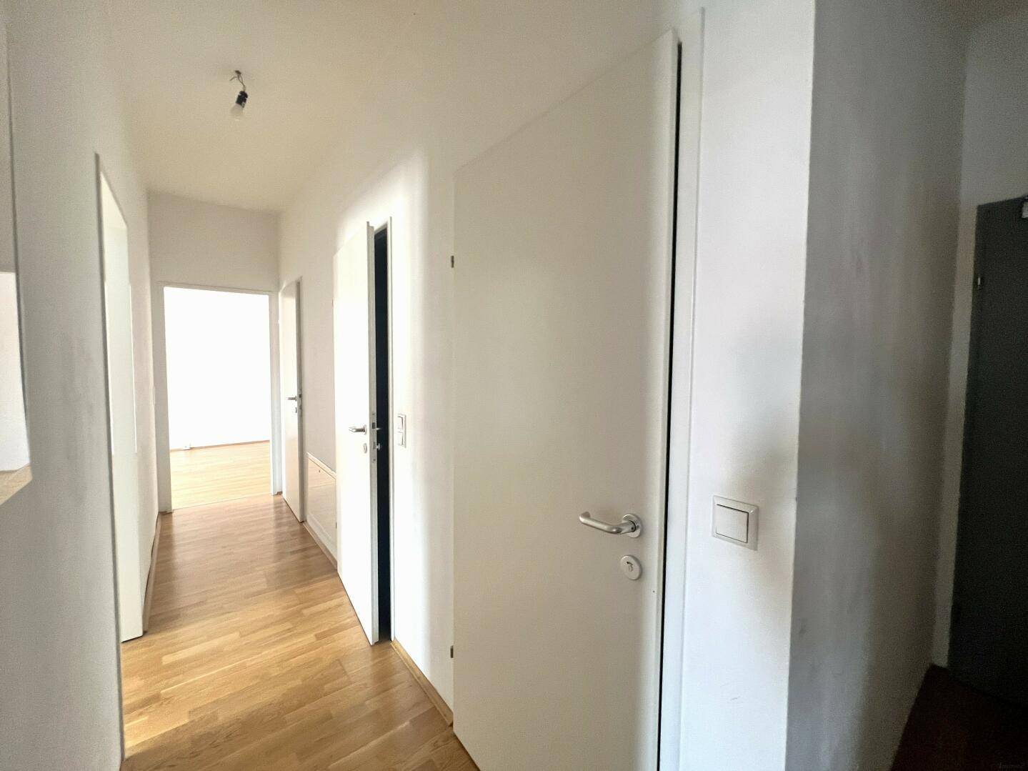 Heller Flur mit mehreren Türen und Holzparkettboden, führt zu den privaten Zimmern.
