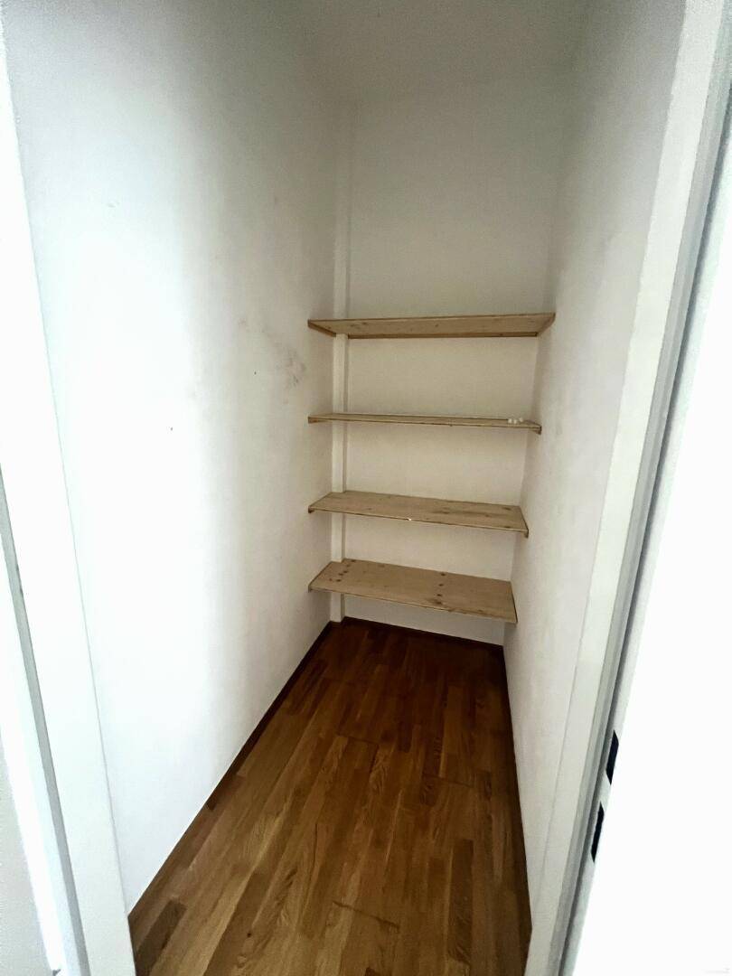 Praktischer Abstellraum mit Holzregalen und Parkettboden für zusätzlichen Stauraum.