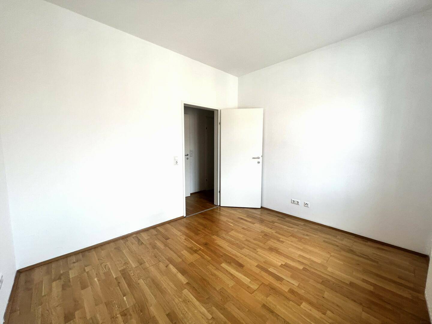 Leerer Raum mit Parkettboden und weiß gestrichenen Wänden, vielseitig nutzbar als Schlaf- oder Arbeitszimmer.