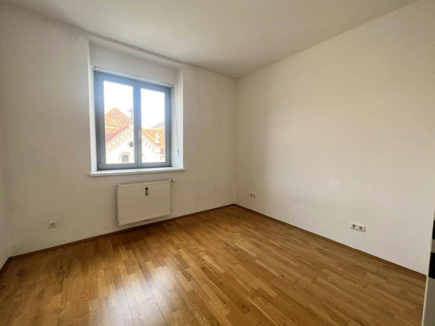 Heller Raum mit Parkettboden und Fenster, ideal als Schlafzimmer oder Kinderzimmer.
