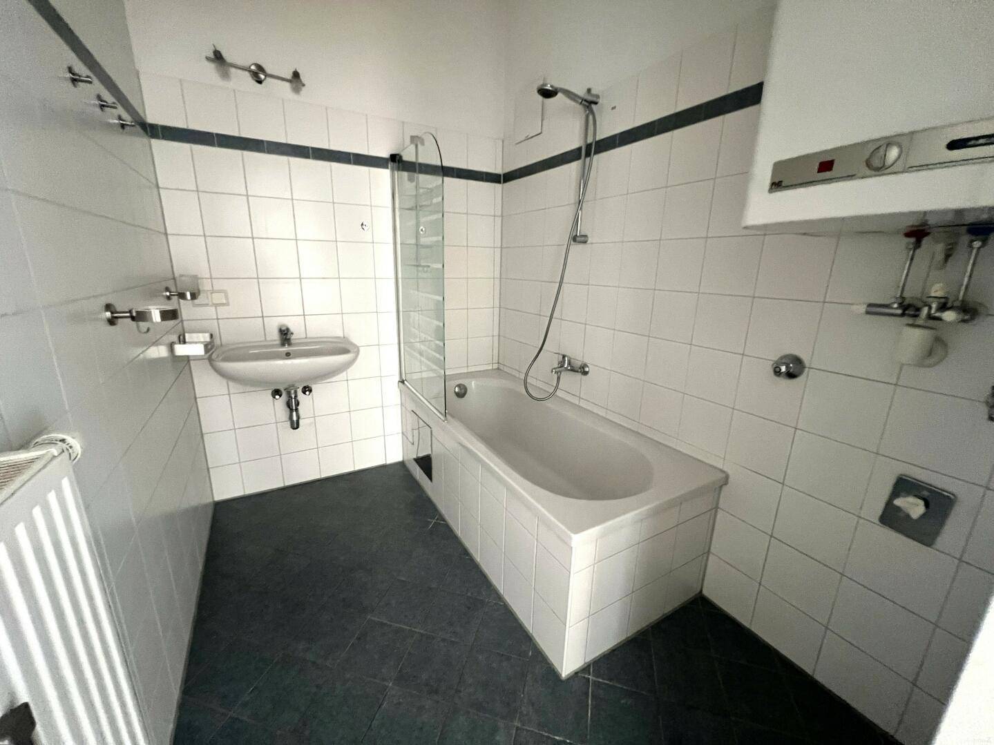 Funktionales Badezimmer mit Badewanne, Waschbecken und weißen Fliesen.
