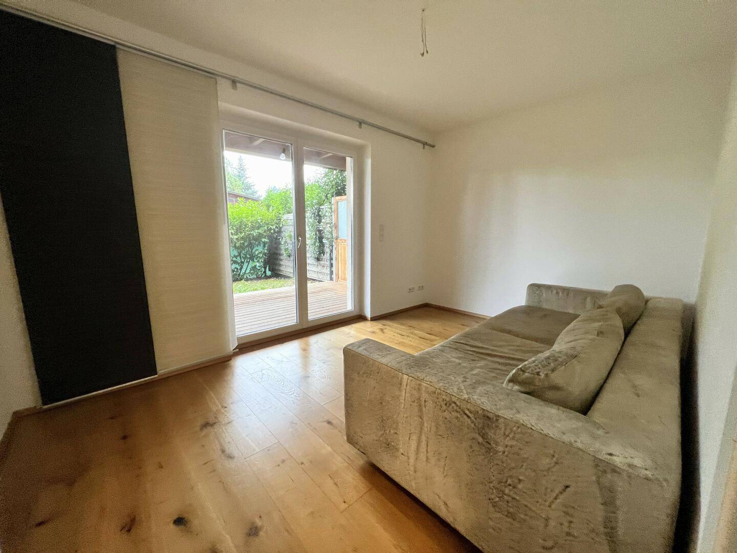 Wohnzimmer mit Sofa, Holzboden und direktem Zugang zur Terrasse.