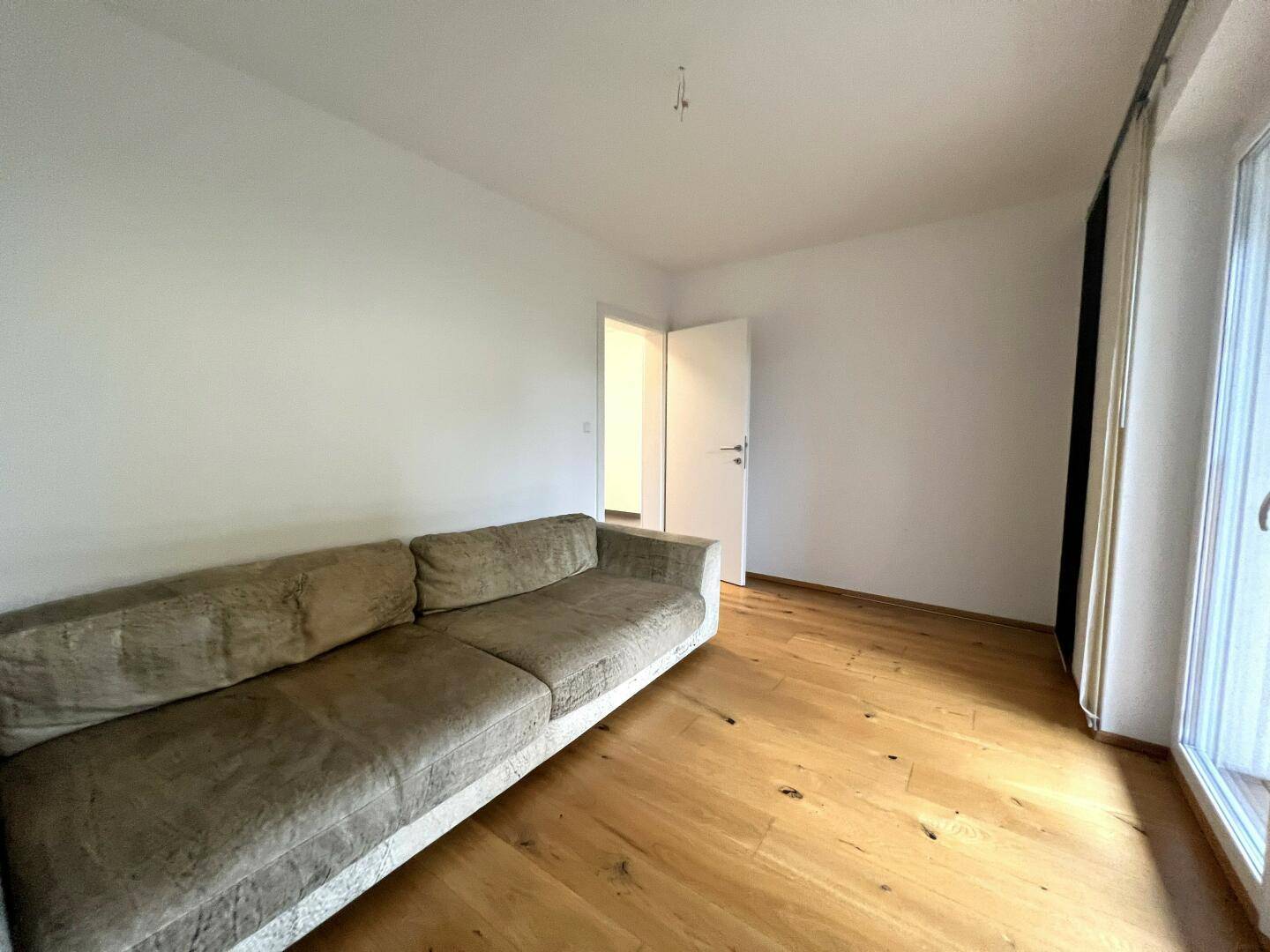 Gemütliches Wohnzimmer mit Sofa, Holzboden und hellem Ambiente.