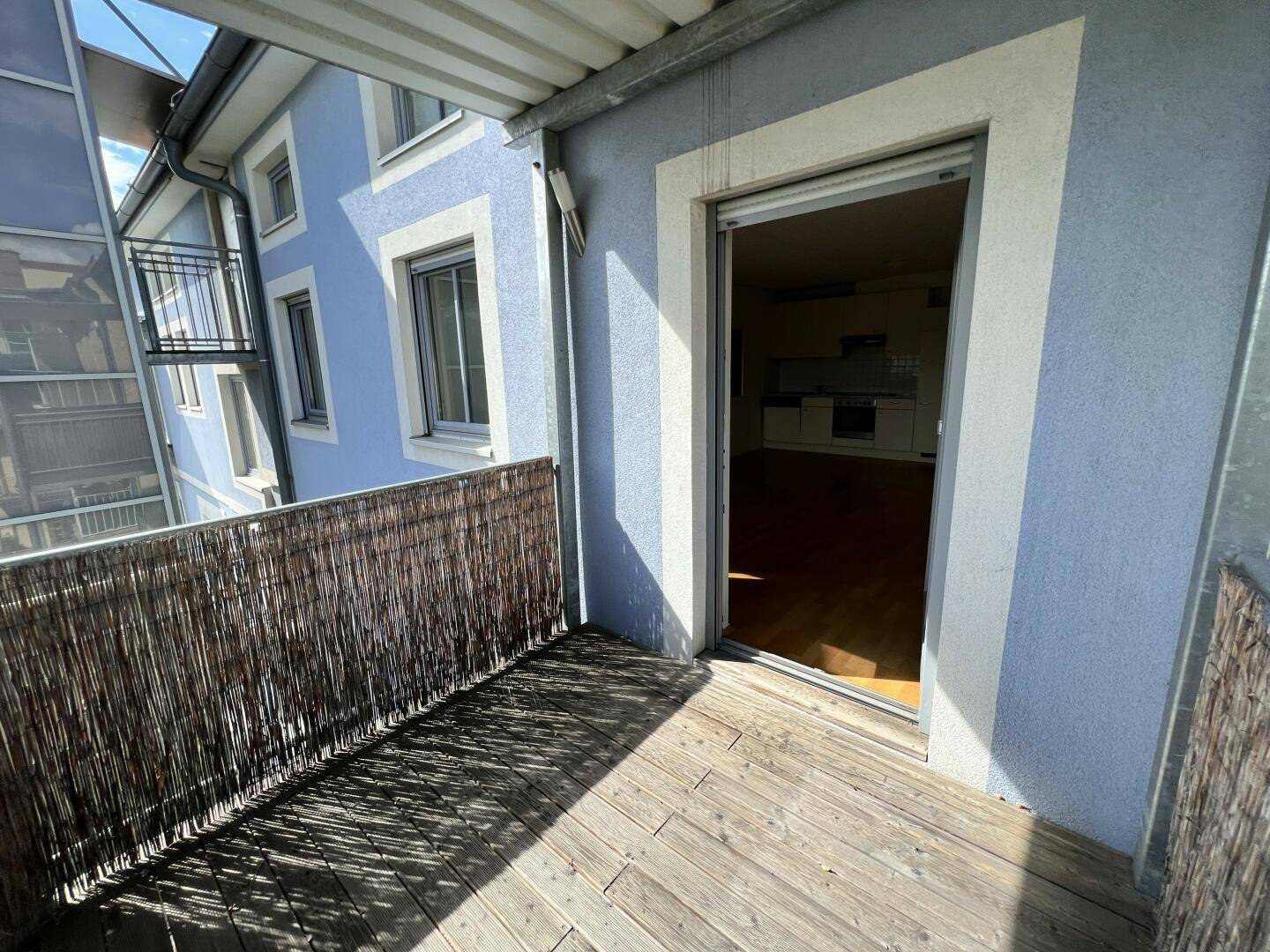 Balkon mit Holzboden und Blick auf die Fassade des Gebäudes und den Innenraum.