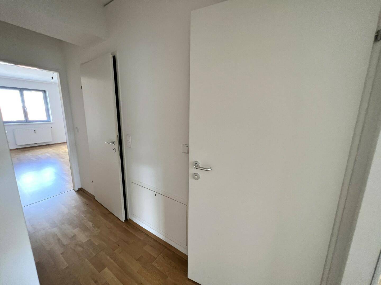 Heller Flur mit Parkettboden und mehreren Türen, die zu den Zimmern führen.