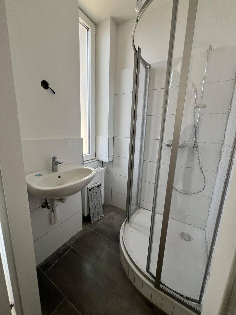 Modernes Badezimmer mit Duschkabine, Waschbecken und Fenster für Tageslicht.