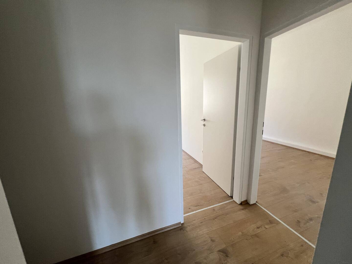 Heller Durchgang mit Laminatboden, der zu weiteren Zimmern der Wohnung führt.