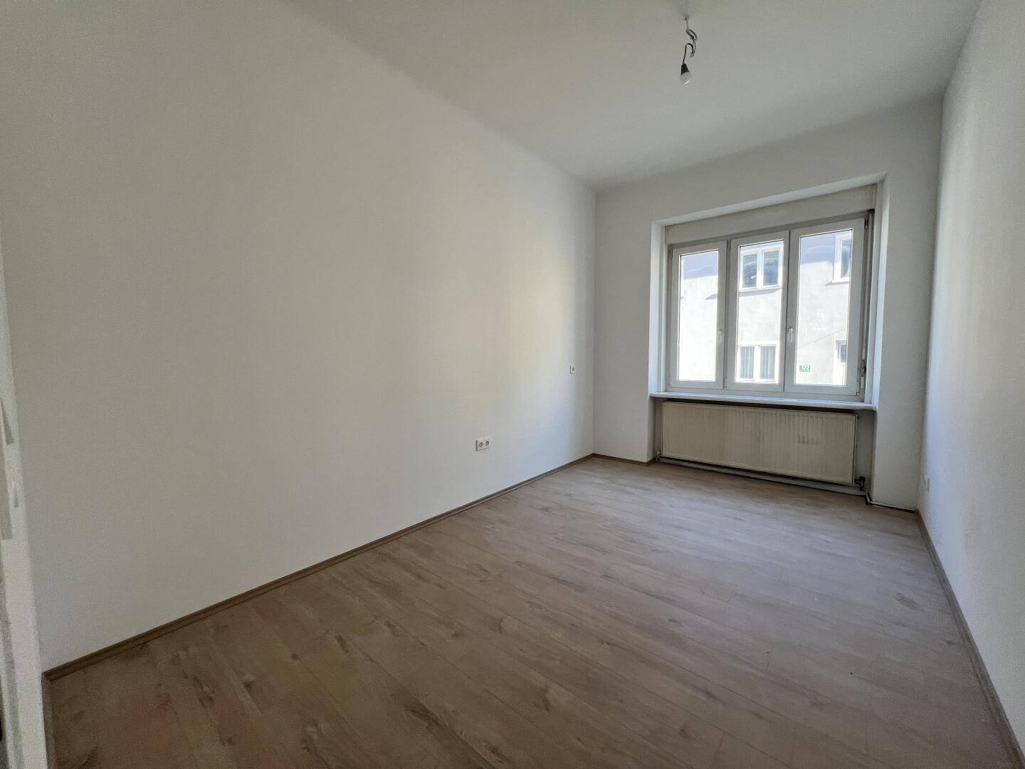 Geräumiges Zimmer mit Laminatboden und großem Fenster, ideal als Wohn- oder Schlafzimmer.