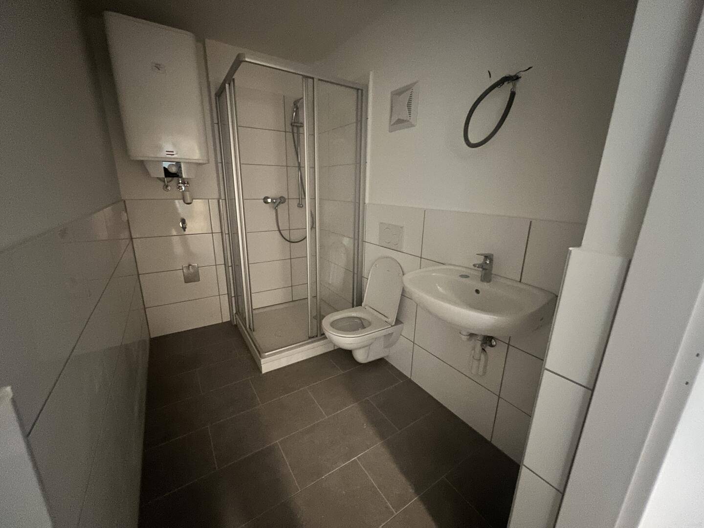 Modernes Badezimmer mit Dusche, WC und Waschbecken, ausgestattet mit weißen Fliesen.