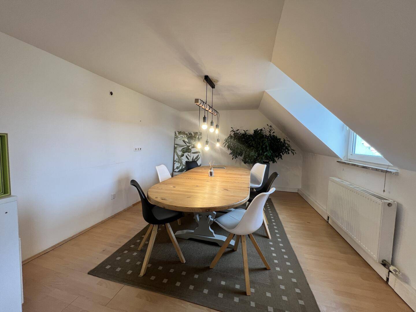 Heller Essbereich im Dachgeschoss mit großem Holztisch, modernen Stühlen und Dachschrägen.