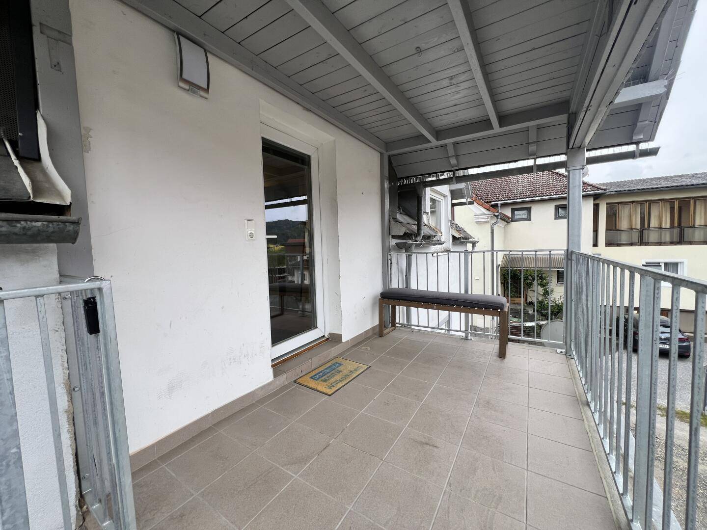 Geräumiger Balkon mit Fliesenboden, Überdachung und Zugang zum Innenbereich.
