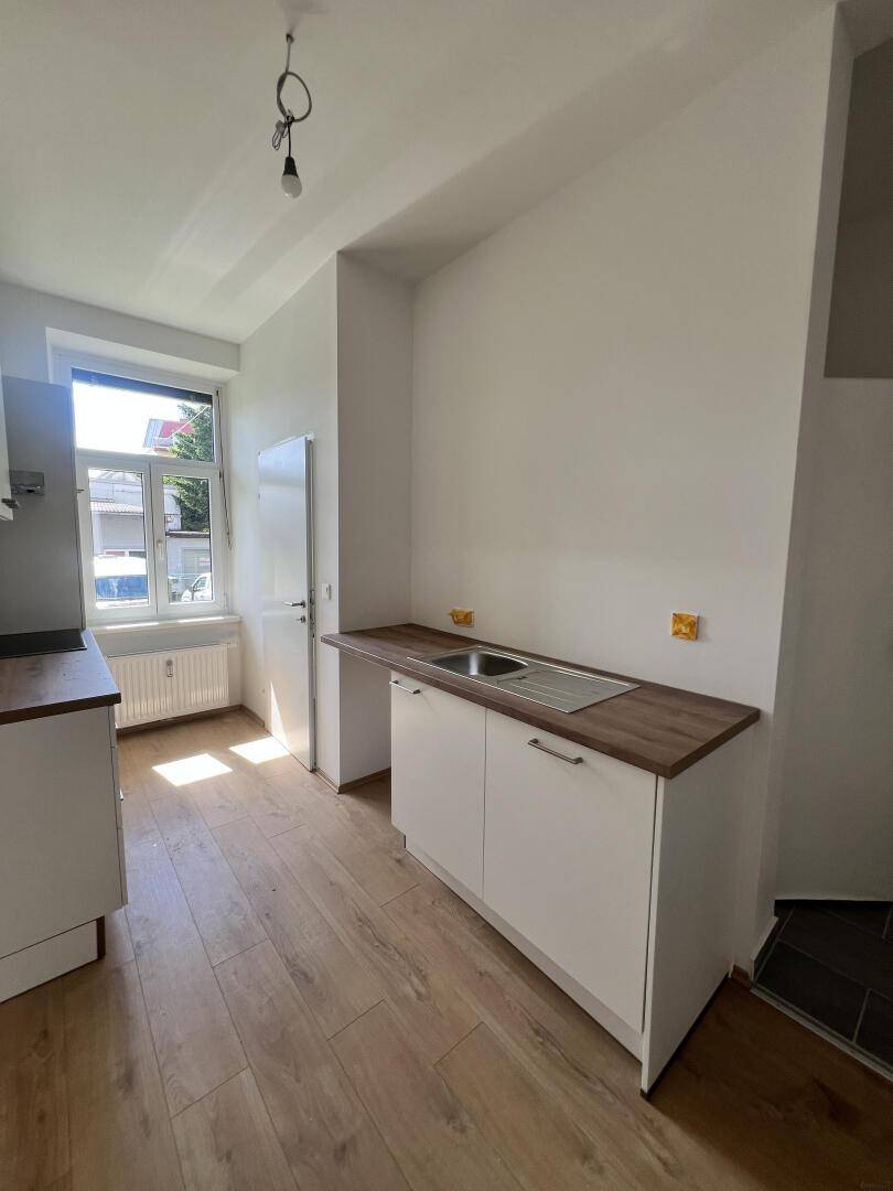 Küche mit Fenster, Spülbecken und Holzarbeitsplatte, bietet Platz für weitere Küchenmöbel.