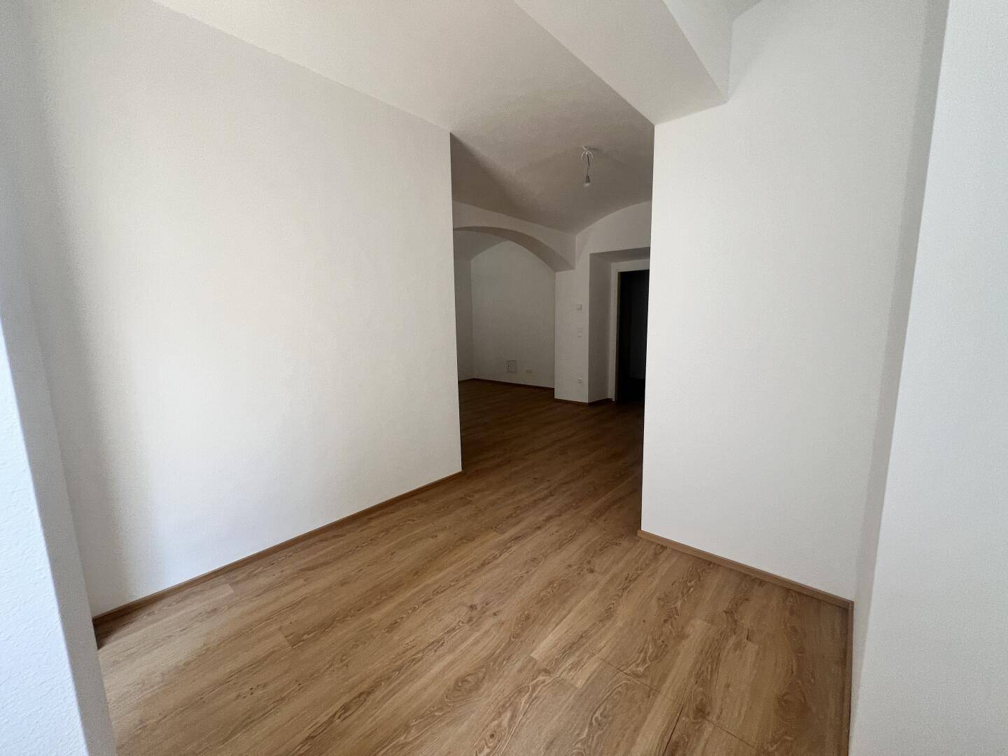 Heller Durchgangsbereich mit Laminatboden, der zu weiteren Zimmern der Wohnung führt.