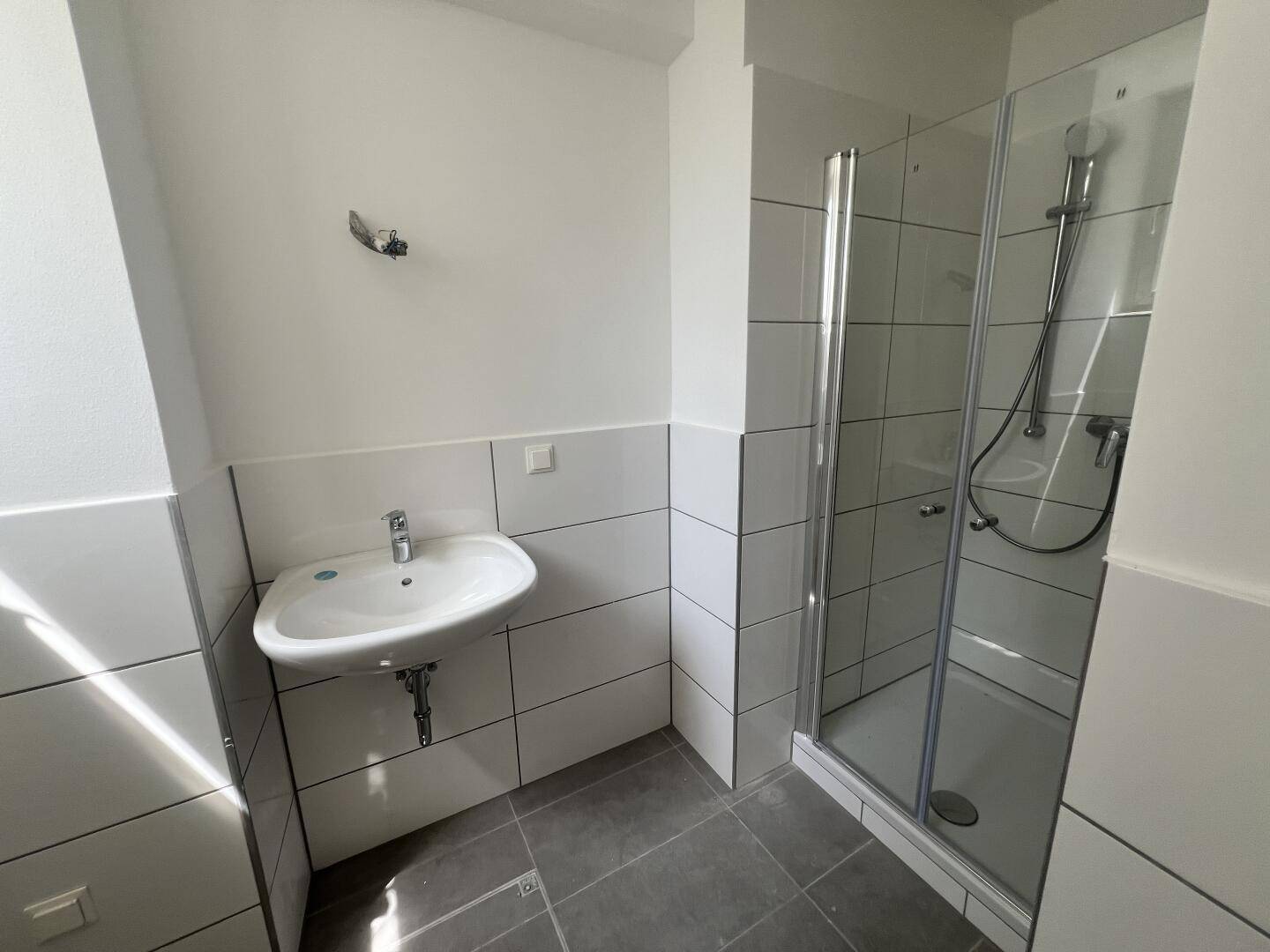 Modernes Badezimmer mit Dusche, Waschbecken und hellen Wandfliesen.