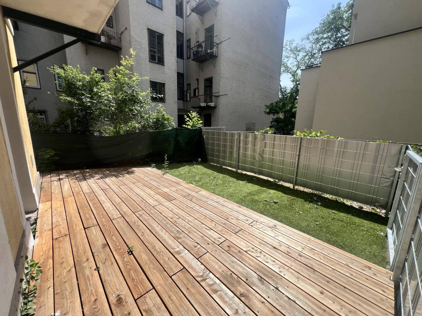 Geräumige Holzterrasse mit Blick auf den Garten und die umliegenden Gebäude.