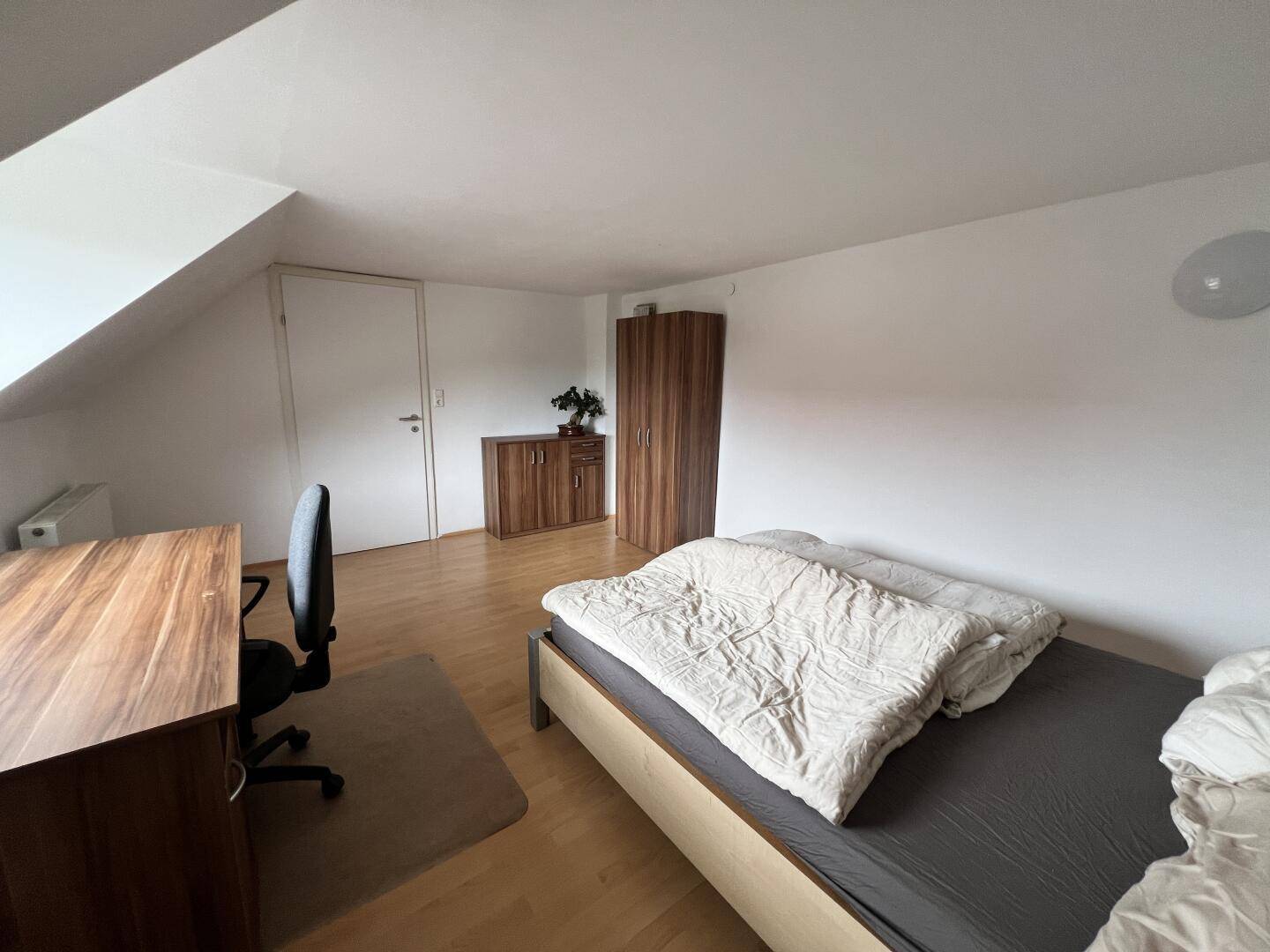 Gemütliches Schlafzimmer mit Schreibtisch, Bett und Kleiderschrank, ideal für Studenten oder Gäste.