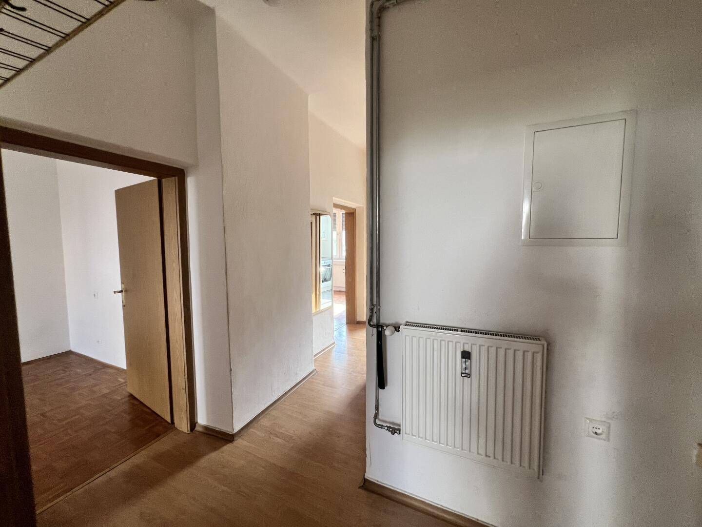 Heller Flur mit Parkettboden, Heizkörper und Zugang zu weiteren Wohnbereichen.
