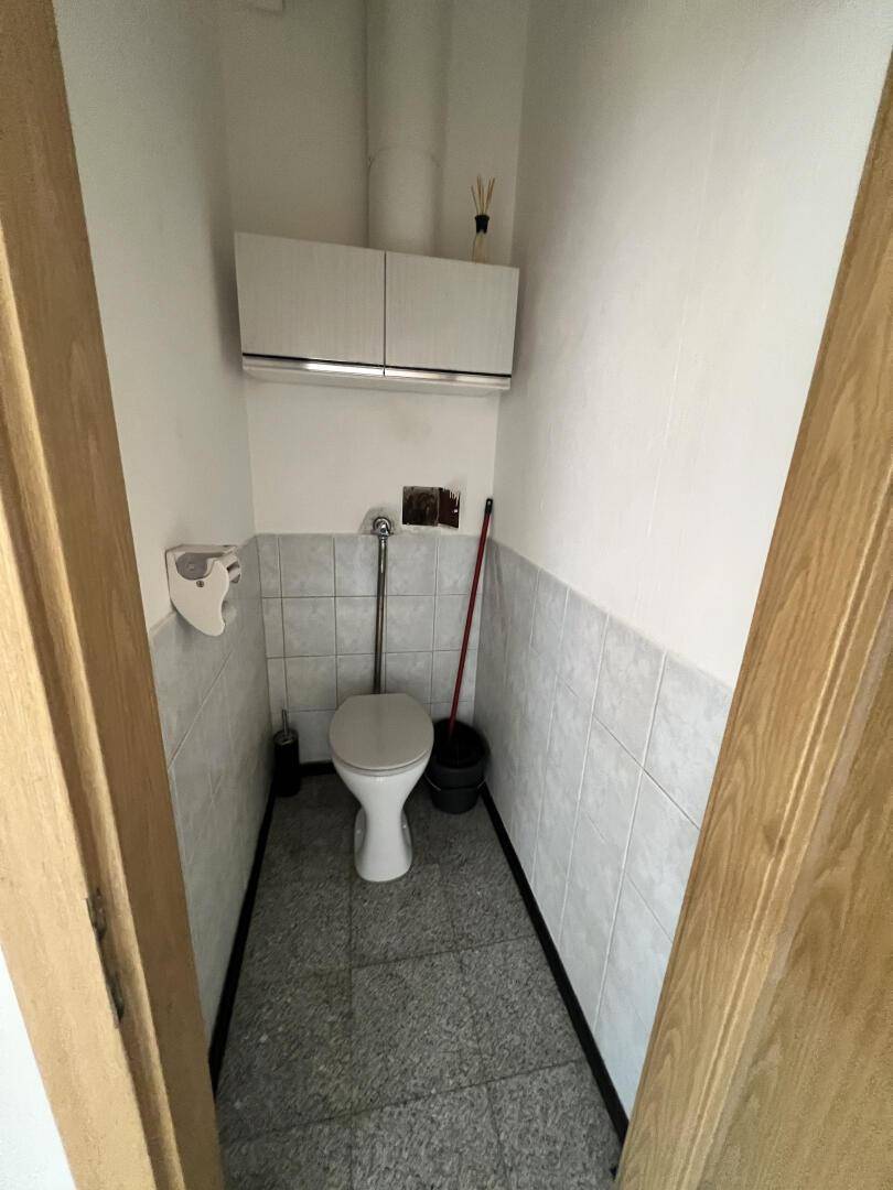 Kleines Gäste-WC mit Fliesenboden, Toilette und Hängeschrank.