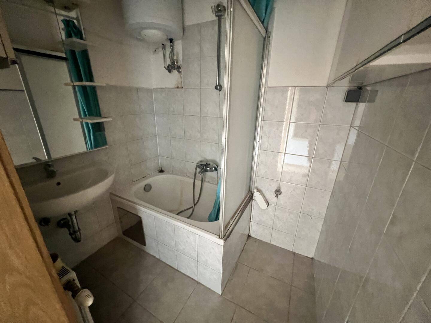 Badezimmer mit Badewanne, Waschbecken und Duschvorhang, in gutem Zustand.