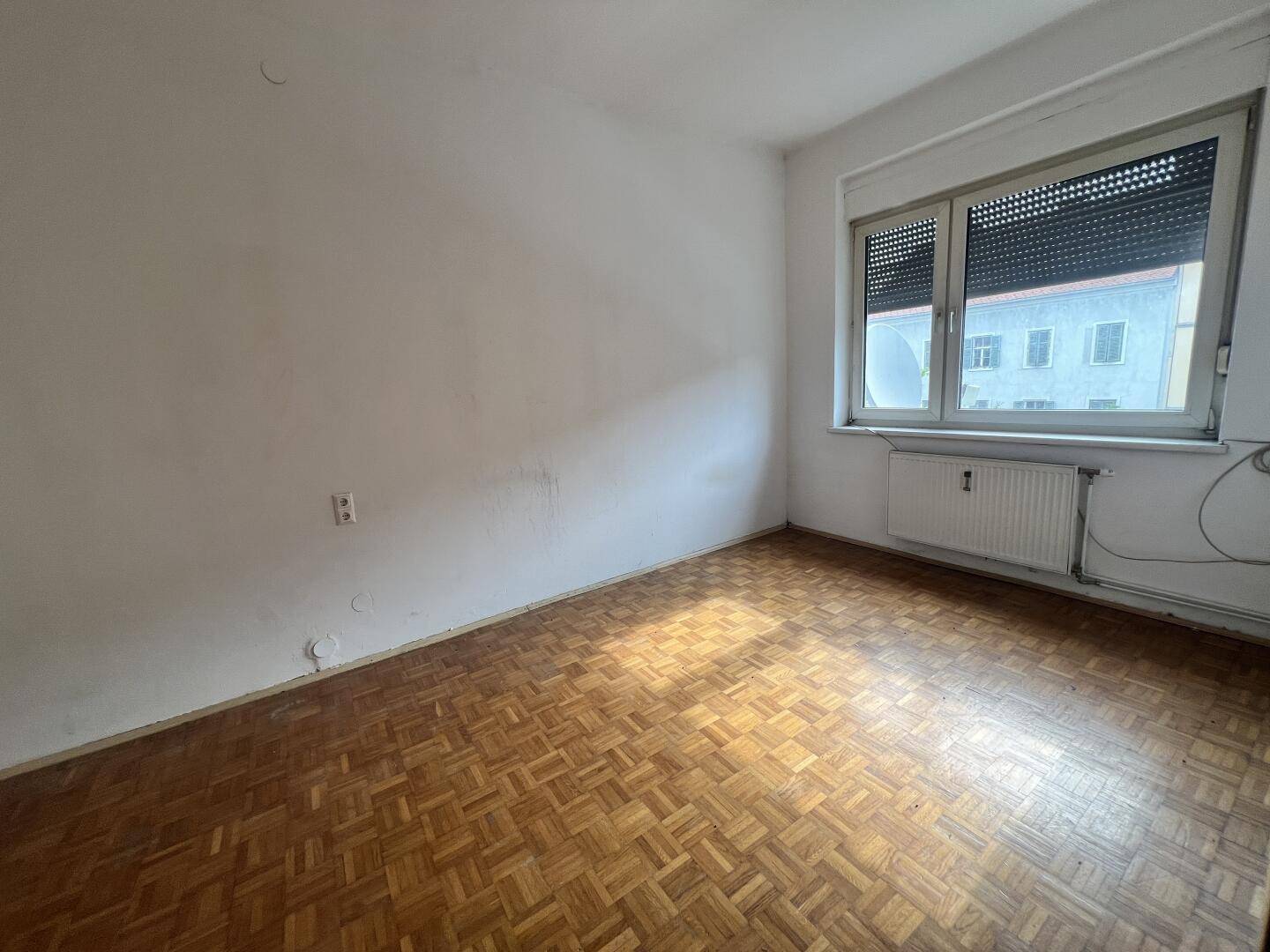 Geräumiges Schlafzimmer mit Parkettboden und großem Fenster, ideal für natürliches Licht.