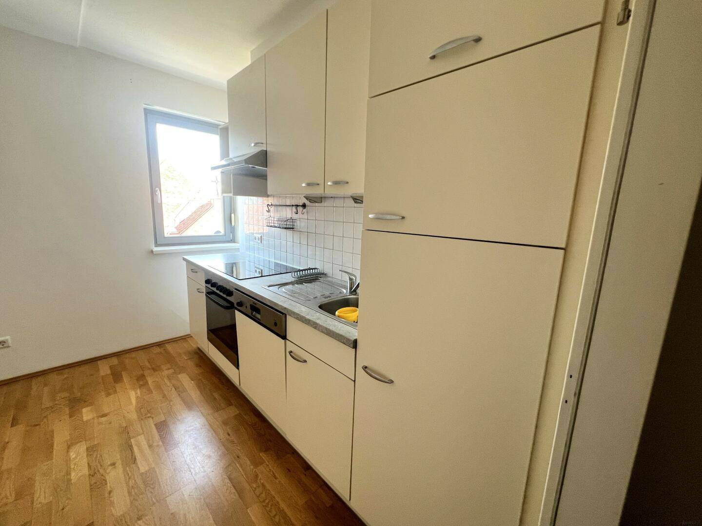 Detailansicht der Einbauküche mit hellen Schränken, Spüle und Kochfeld.