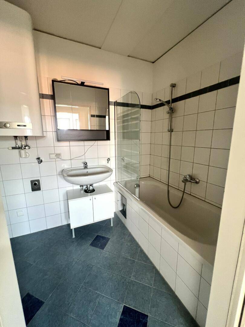 Badezimmer mit Badewanne, Waschbecken und blauen Bodenfliesen.